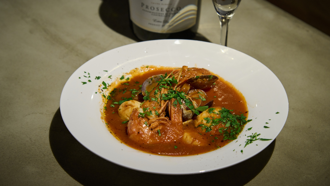 Seafood Tomato Stew with shrimp, scallops, and clams, flavored with melon juice, served in a white bow