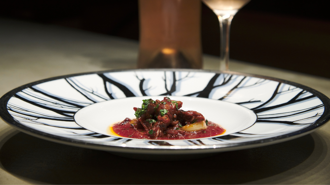 Stewed Firefly Squid in rich tomato sauce, garnished with herbs, served in a skillet