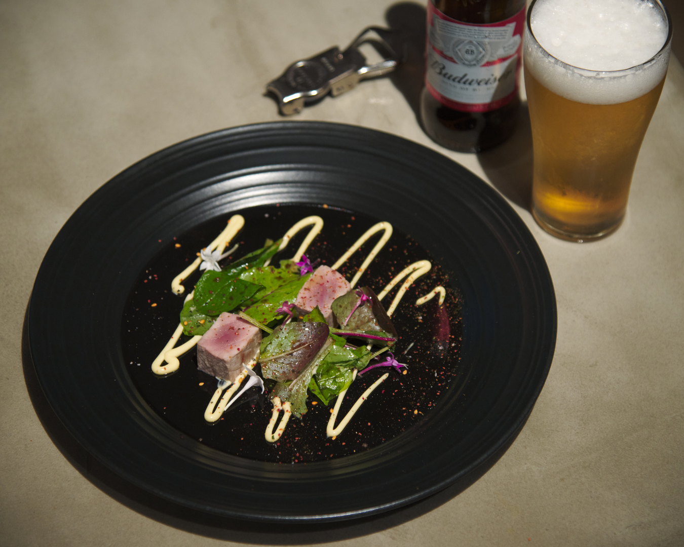 Seared Bonito Rare Steak served with balsamic baby leaf salad and lemon zest on a plate